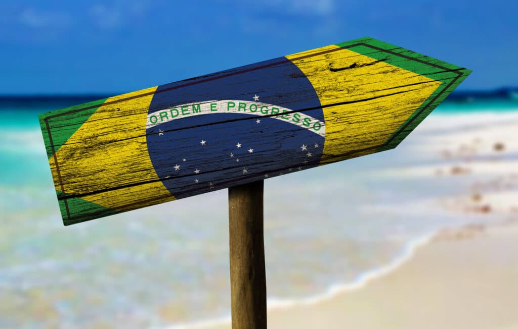 Brazil flag wooden sign with a beach on background - Latin America